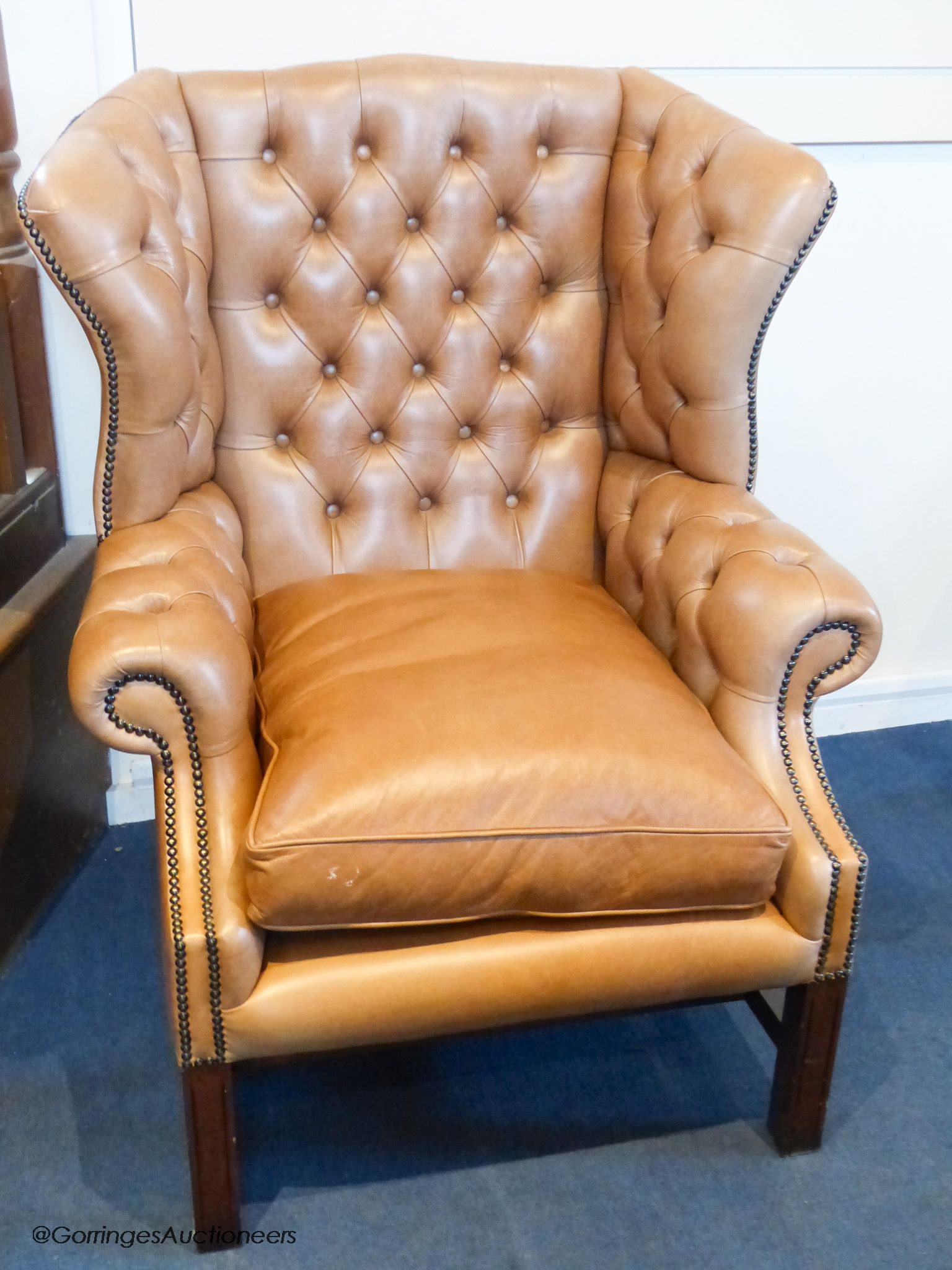 A George III style buttoned tan leather wingback armchair
